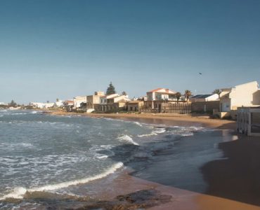Beautiful coastal view of a sandy beach in Sicily, Italy under a clear blue sky.